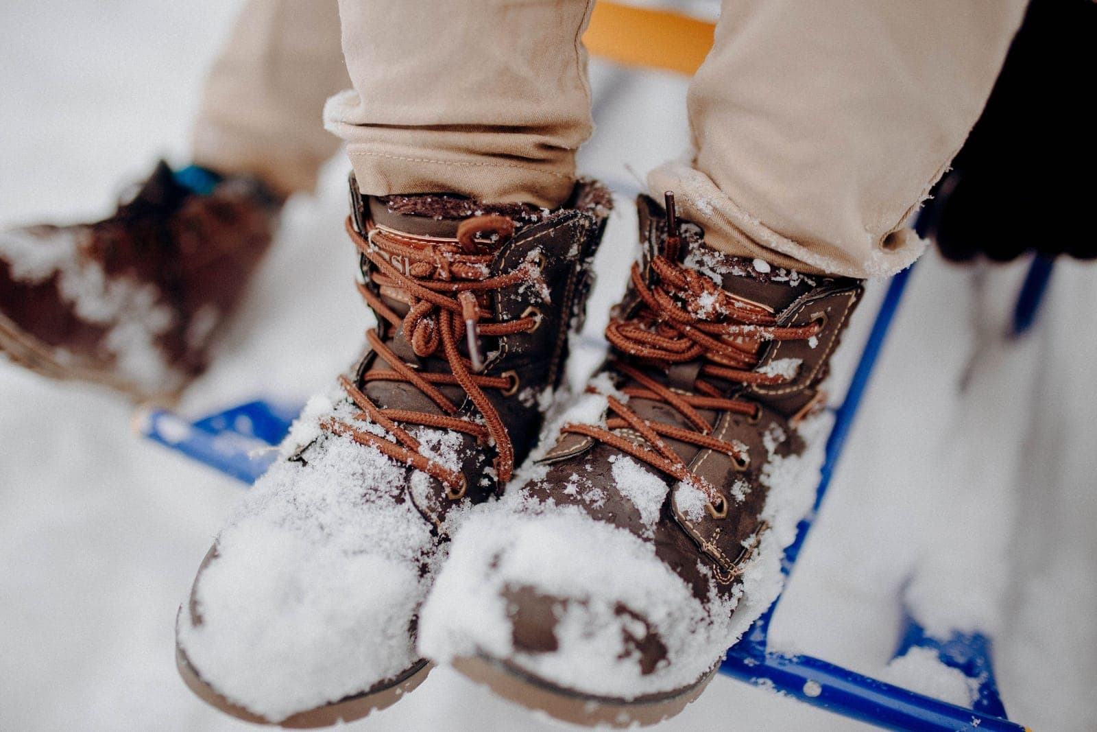 Brown winter boots covered in snow on a snowy day