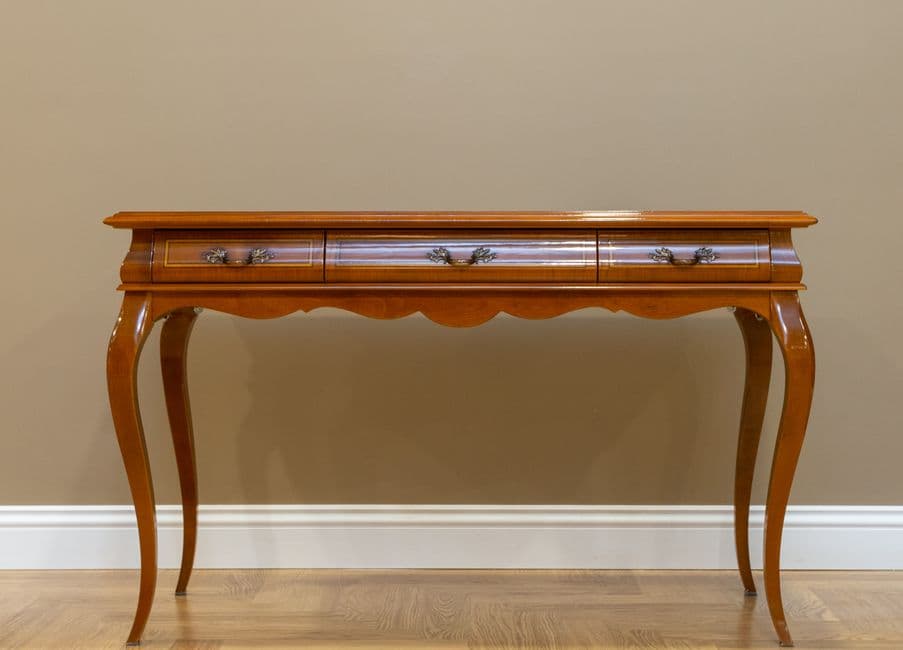 A classic wooden console table with metal handles against a plain wall