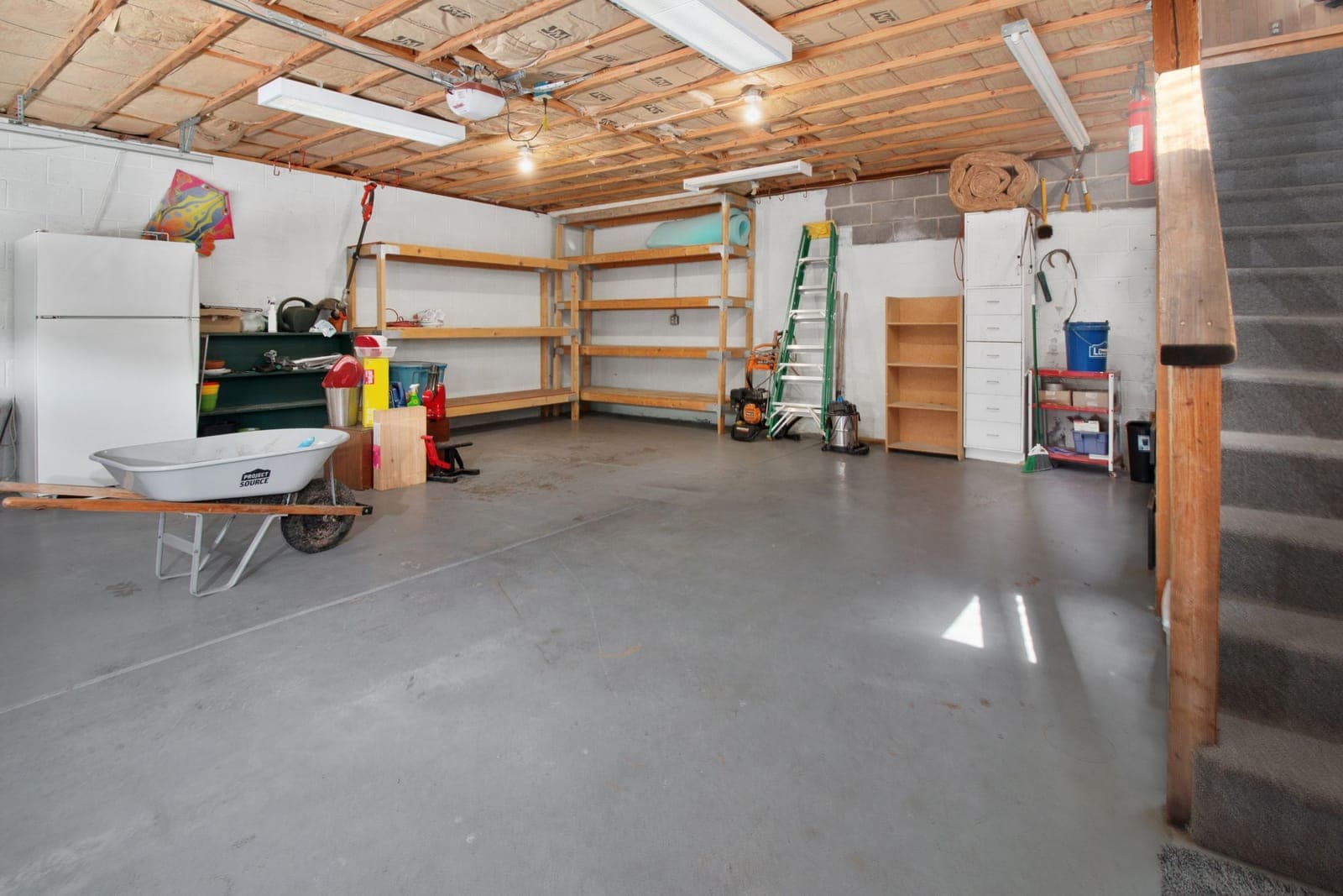 A spacious garage interior with storage shelving and tools along the wall