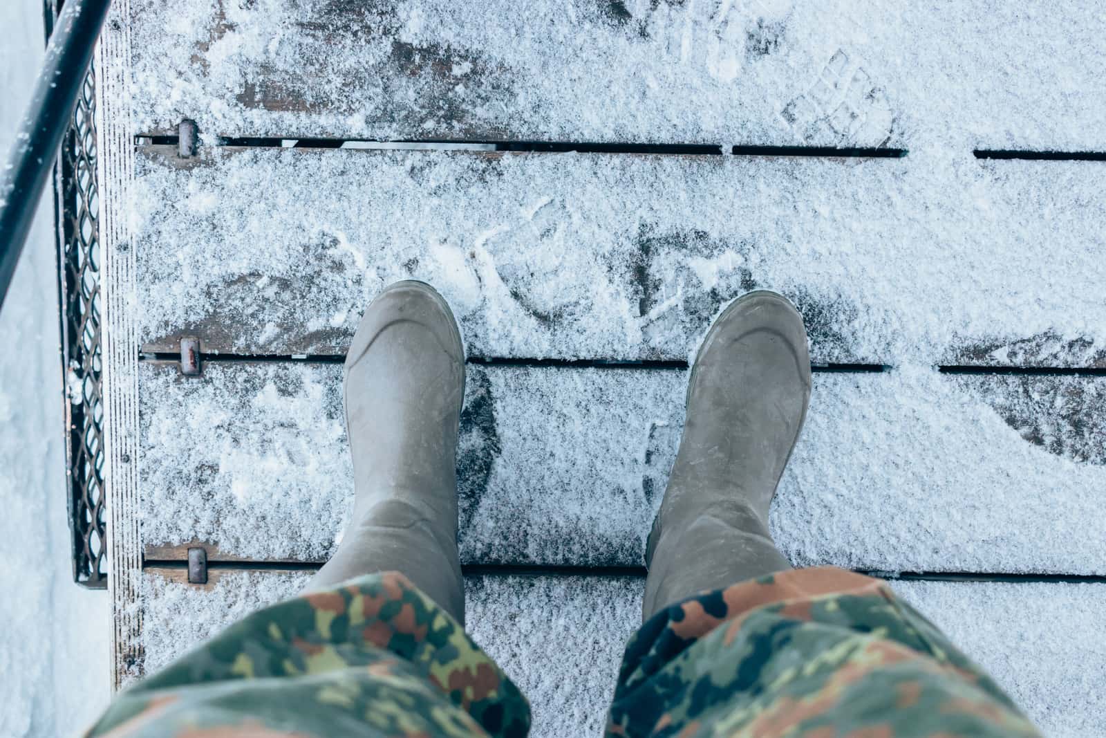 Winter boots standing on a snow-covered wooden step outside a door