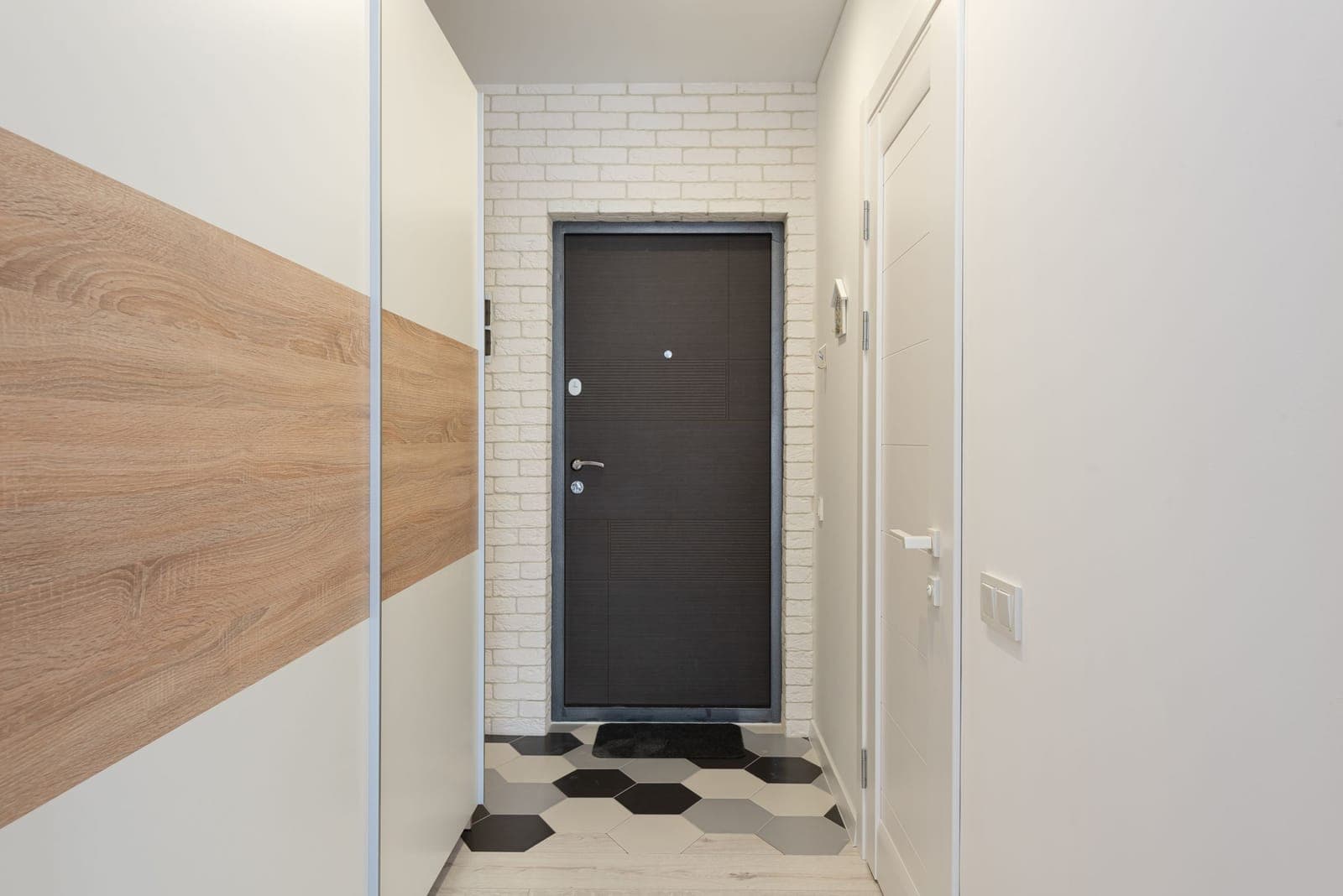 A narrow home corridor with a runner on the floor and doors along one side