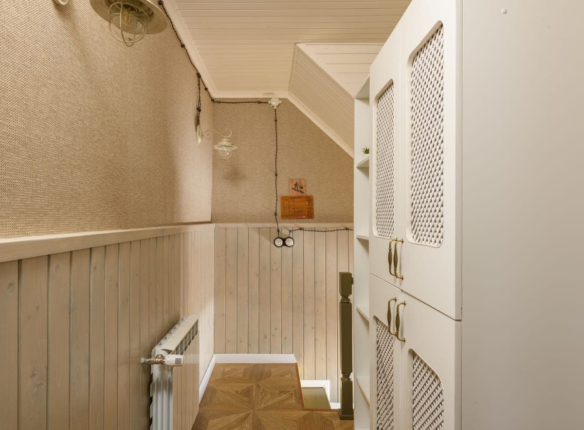 A narrow shoe cabinet against the wall of a slim entryway hall