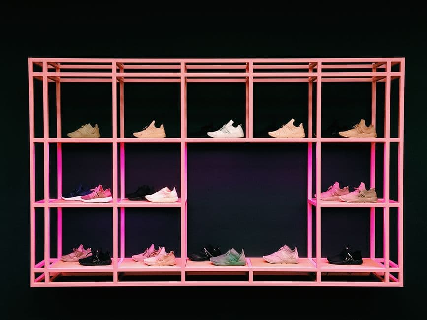 Colorful sneakers arranged in rows on a pink shelf