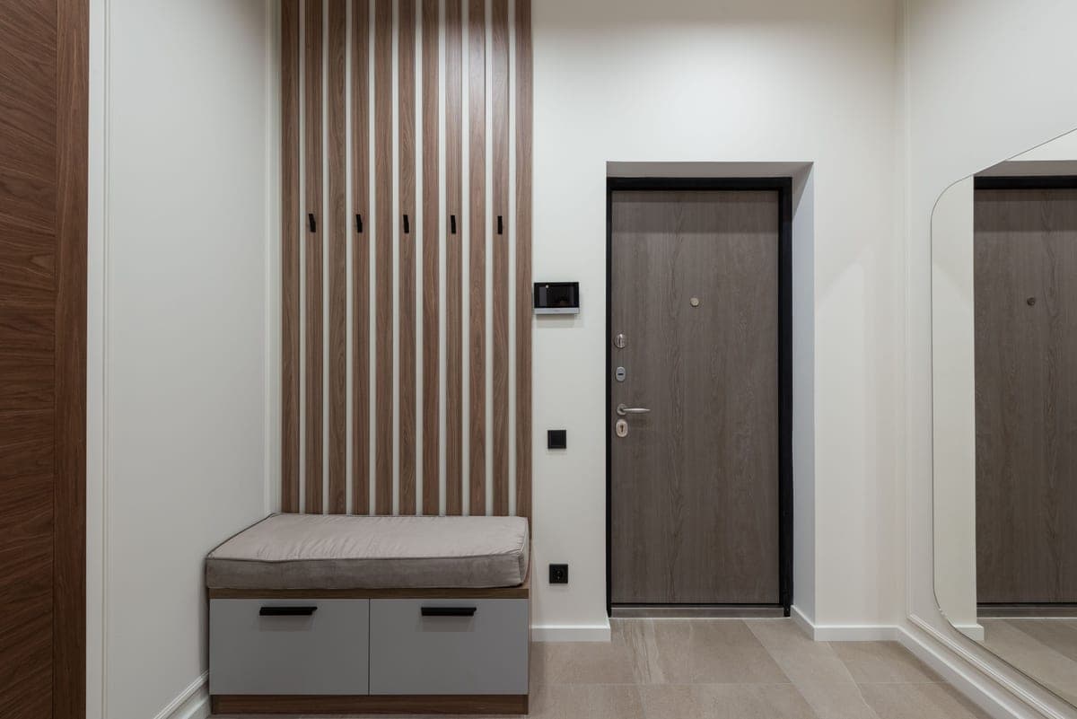 A shoe storage bench with shoes stored underneath in an entryway