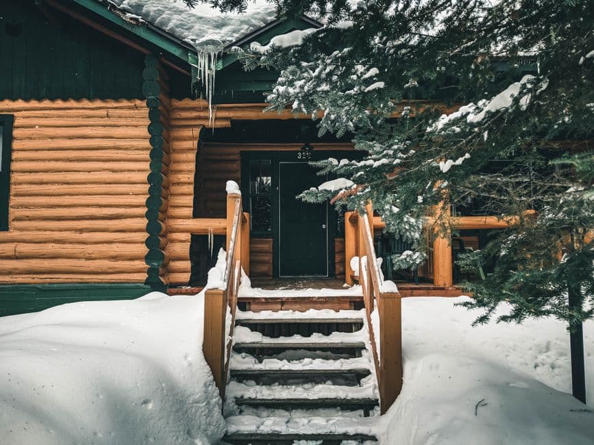Snow-covered wooden steps leading up to the entrance of a cabin in winter