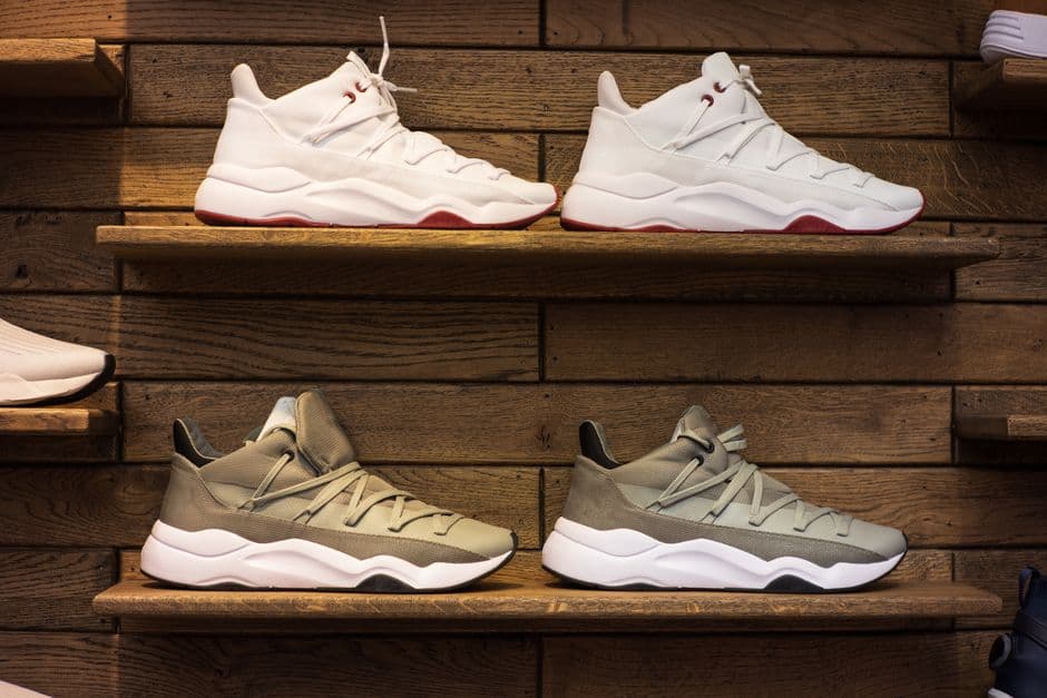 Sneakers lined up on shallow shelves mounted to a wooden wall