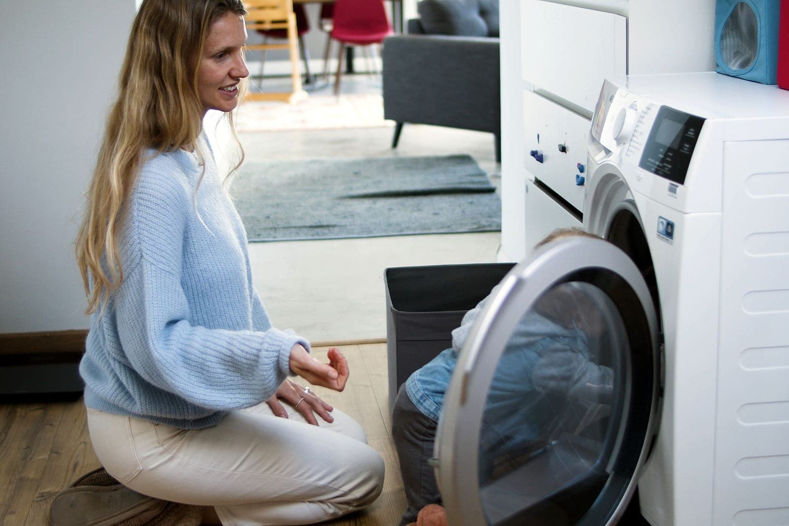 A woman and child loading a washing machine at home