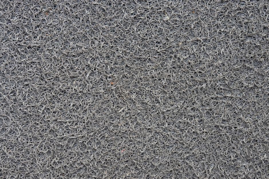 Close-up of a gray synthetic door mat showing its looped fiber pile
