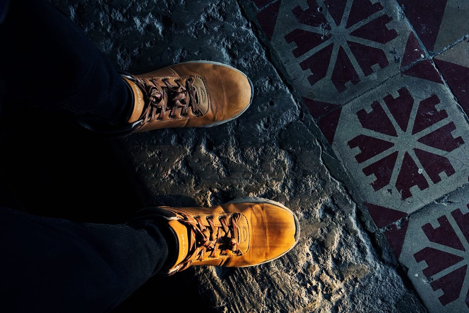 Brown boots seen from above on a patterned tile floor indoors