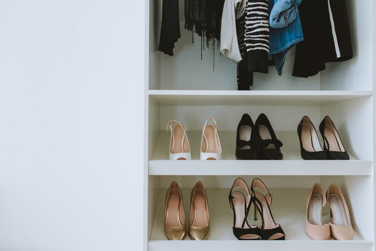 An open shoe shelf beside a closed shoe cabinet in a hallway