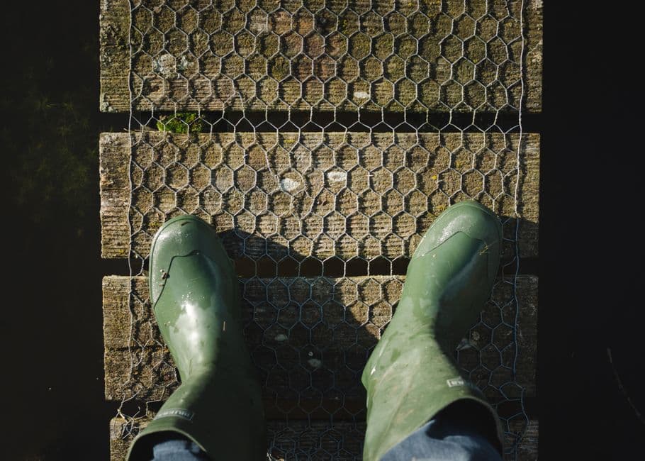 Overhead view of a pair of green rubber boots on weathered wood