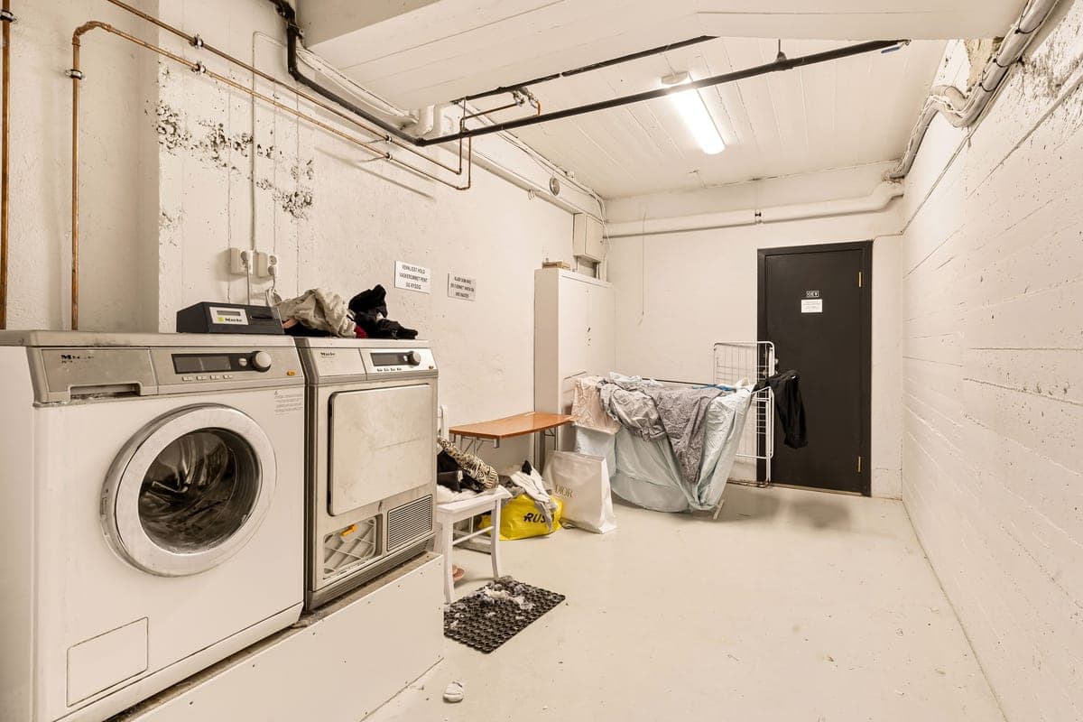 A door mat being hosed clean outside next to a washing machine load