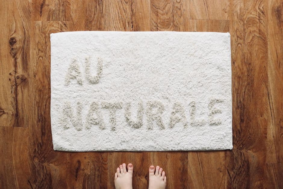 A white doormat lying on a wooden floor, seen from above