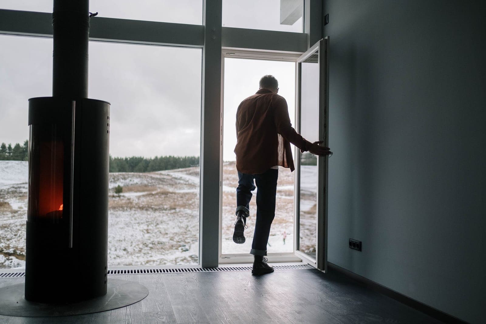 A person stepping out of a house door into deep snow